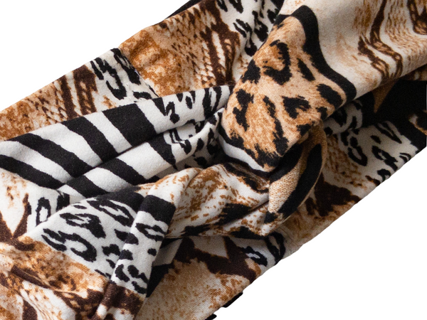 "Close up view, showing twisted front, multi animal print headband with black, white, and blends of browns."